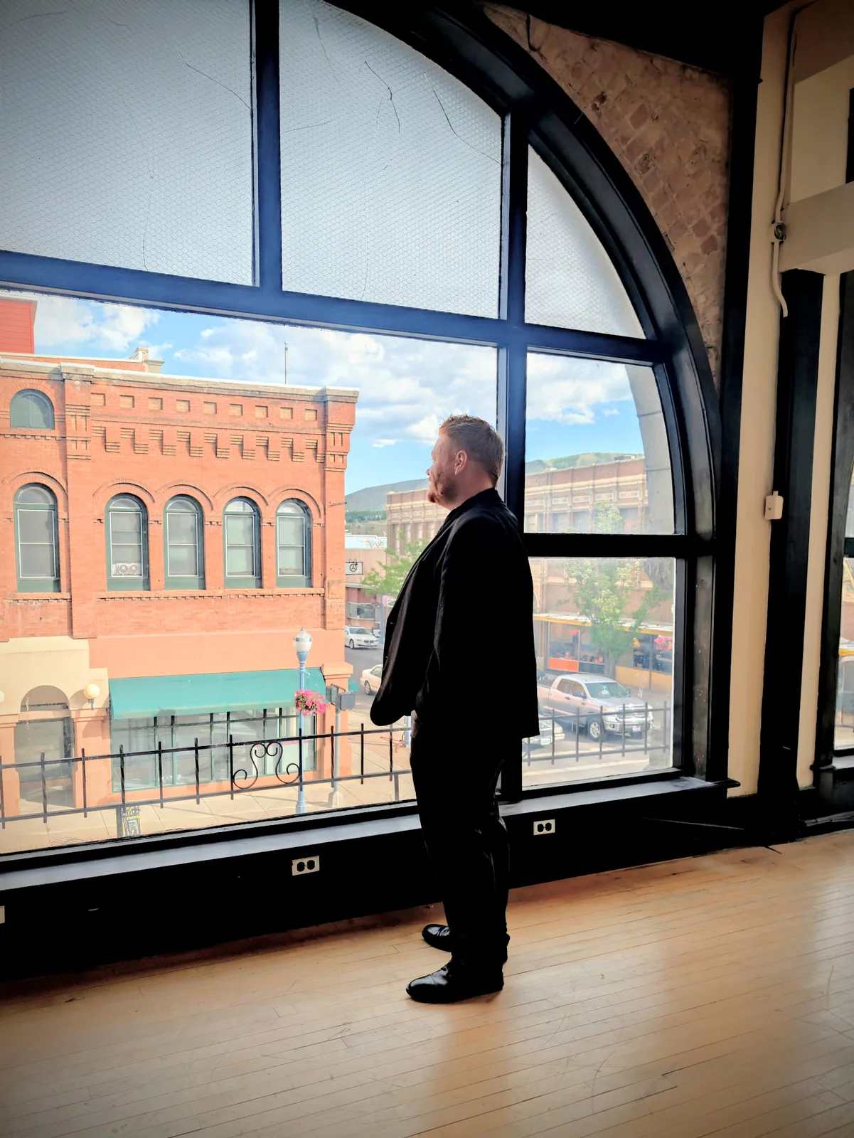 Morgan McKell looking out an arched window over the historic brick buildings of Old Town Pocatello, Idaho